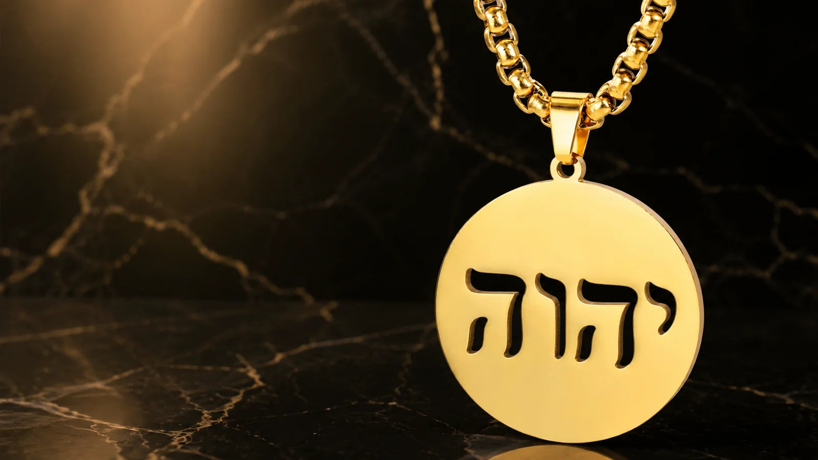 Gold YHWH pendant on a chain against black marble